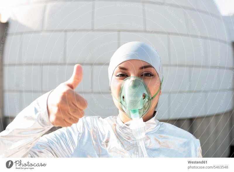 Frau mit Schutzanzug und Sauerstoffmaske zeigt Daumen nach oben, während sie gegen Iglu steht Farbaufnahme Farbe Farbfoto Farbphoto Außenaufnahme außen draußen
