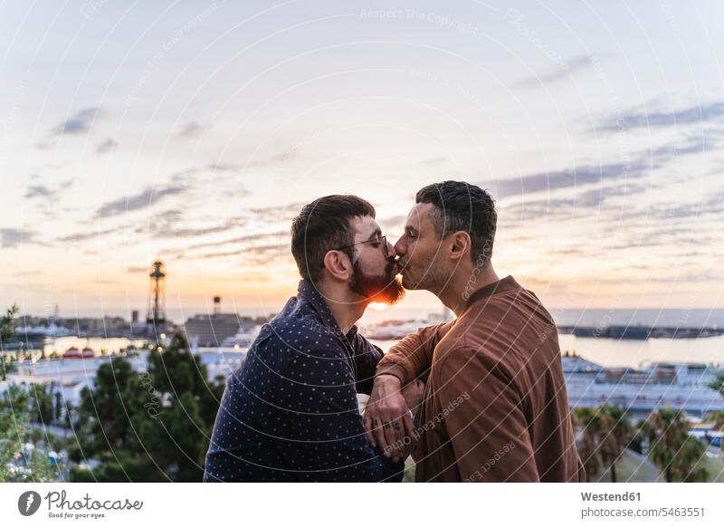 Schwules Paar küsst sich auf einem Aussichtspunkt über der Stadt mit Blick auf den Hafen, Barcelona, Spanien Leute Menschen People Person Personen Europäisch