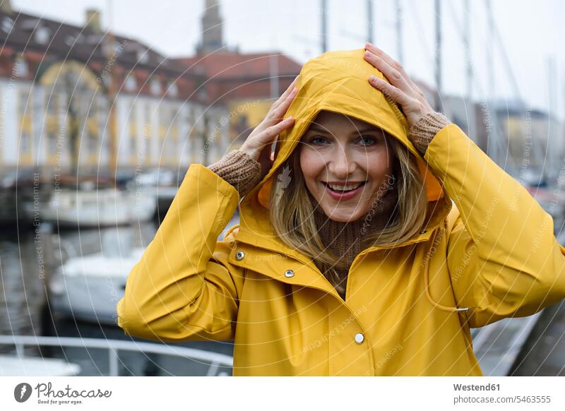 Dänemark, Kopenhagen, Porträt einer glücklichen Frau am Stadthafen bei regnerischem Wetter weiblich Frauen Regenwetter Hafen Haefen Häfen Glück glücklich sein