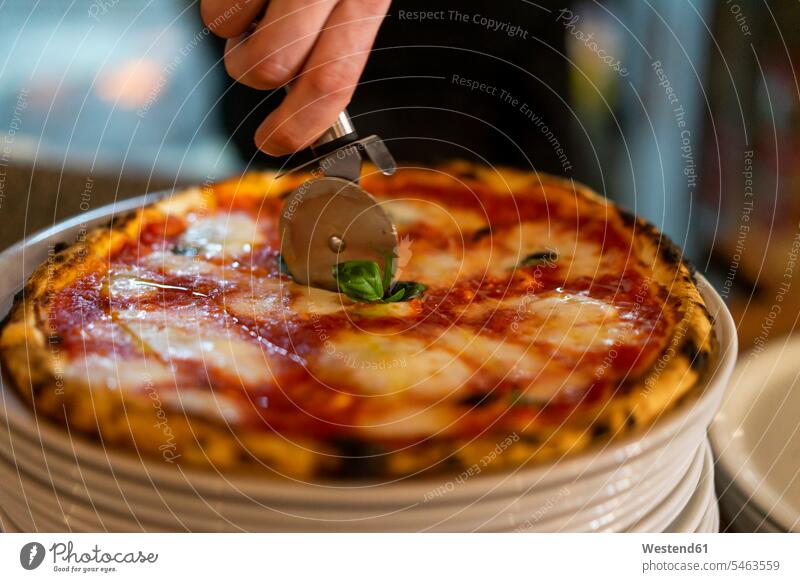 Schneiden einer Pizza auf einem Stapel von Tellern schneiden gestapelt Haufen Küche Pizzen Anordnung Positionierung Anordnungen Arrangements Positionierungen