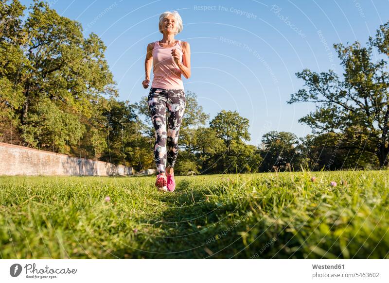 Ältere Frau läuft auf ländlicher Wiese weiblich Frauen laufen rennen auf dem Land auf dem Lande Wiesen Seniorin älter Seniorinnen alt Erwachsener erwachsen