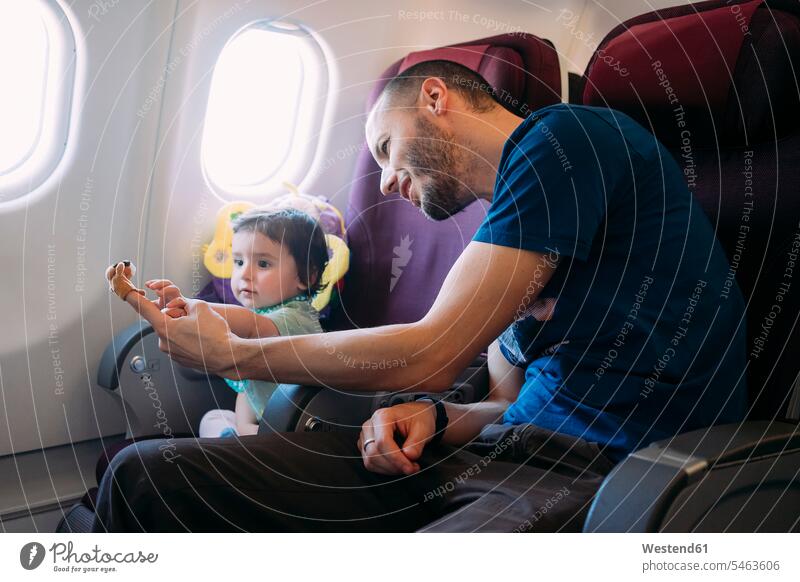 Vater spielt mit seiner kleinen Tochter im Flugzeug Väter Papa Vati Familienvater Papi reisen Travel verreisen Weg Reise Flugreise Flugreisen Flüge Fluege
