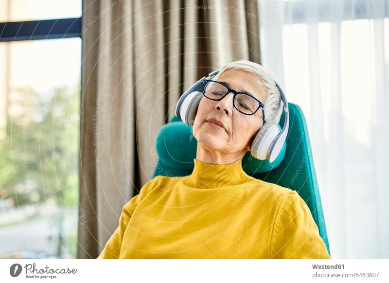 Ältere Frau schlafend im Sessel mit Kopfhörer auf Leute Menschen People Person Personen Europäisch Kaukasier kaukasisch erwachsen Erwachsene Frauen weiblich