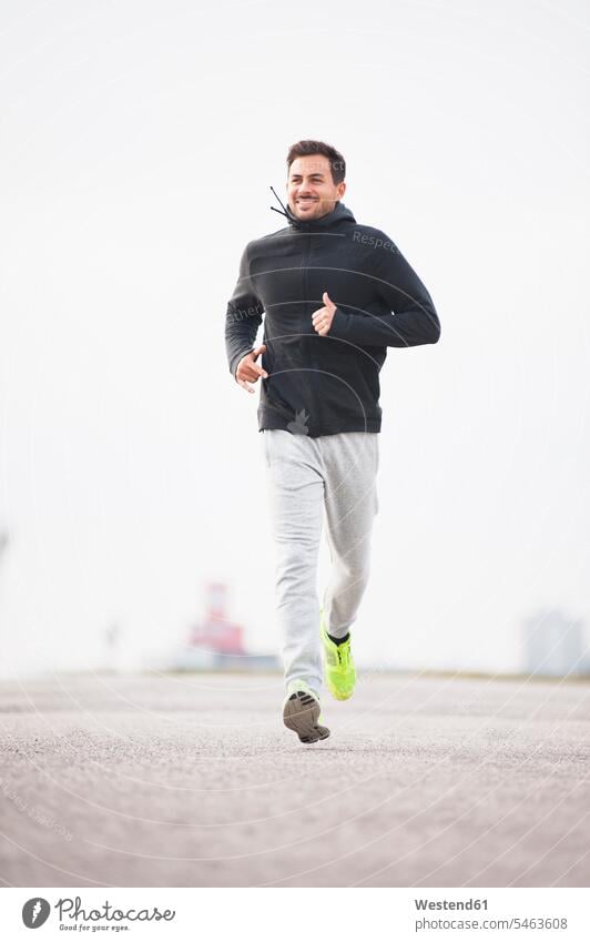 Junger Mann rennt auf einer Fahrbahn rennen freuen fit gesund Gesundheit Muße Jogging Anreiz Ansporn Antrieb motivieren motiviert Spass spassig spaßig Spässe