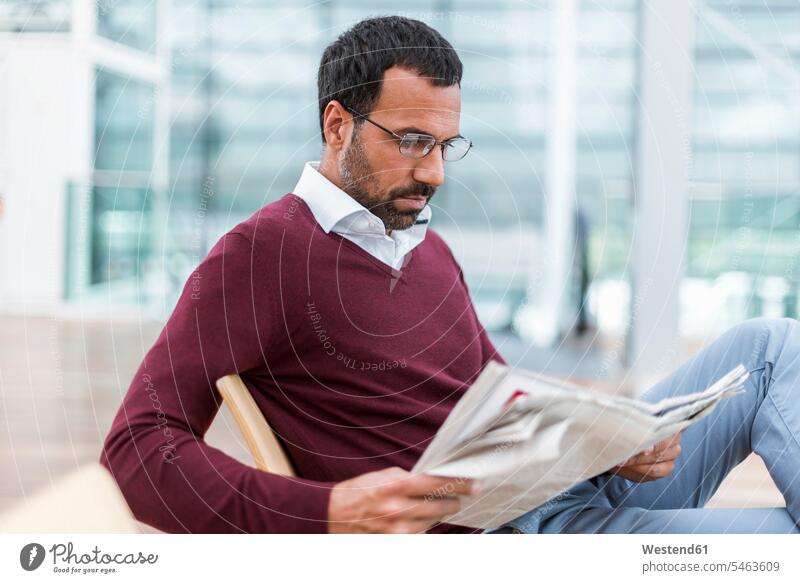 Geschäftsmann liest eine Zeitung im Wartesaal Mann Männer männlich Zeitungen warten Brille Brillen lesen Lektüre Businessmann Businessmänner Geschäftsmänner