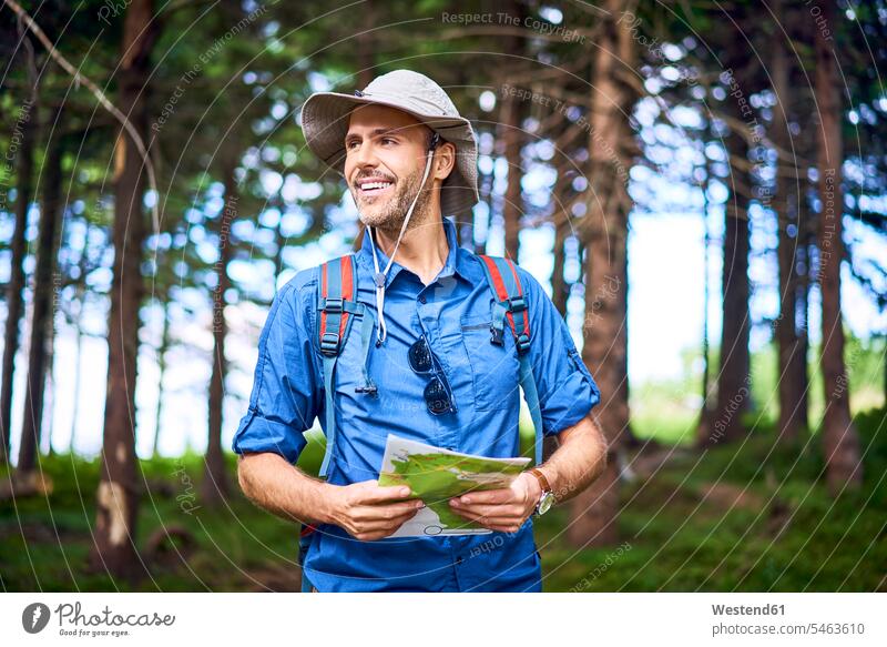 Lächelnder Mann mit einer Karte in der Hand wandert im Wald Forst Wälder Männer männlich wandern Wanderung lächeln Landkarte Landkarten Erwachsener erwachsen