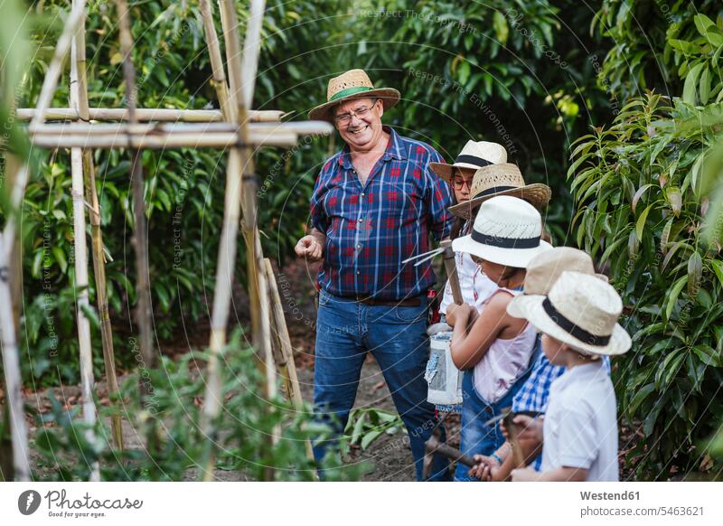 Grossvater mit Kindergruppe im Garten freuen Glück glücklich sein glücklichsein zufrieden Gartenarbeit Gartenbau Muße Miteinander Zusammen Bindung Gemeinschaft