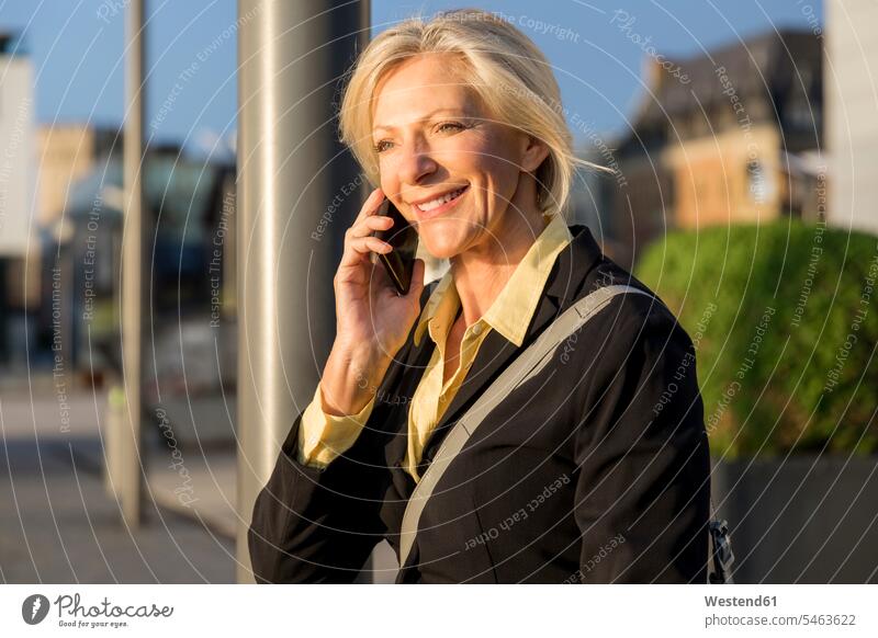 Lächelnde ältere Geschäftsfrau am Mobiltelefon im Freien Geschäftsfrauen Businesswomen Businessfrauen Businesswoman lächeln Handy Handies Handys Mobiltelefone