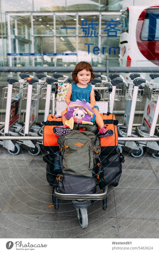 Baby Mädchen sitzt auf der Oberseite des Gepäcks in einem Trolley am Flughafen Flughaefen Flugplätze Airport Flugplaetze Airports Terminals Flugplatz Flughäfen