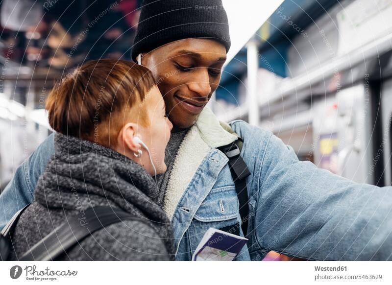 Porträt eines jungen Paares, das sich in einer U-Bahn Ohrstöpsel teilt Leute Menschen People Person Personen Afrikanisch Afrikanische Abstammung dunkelhäutig