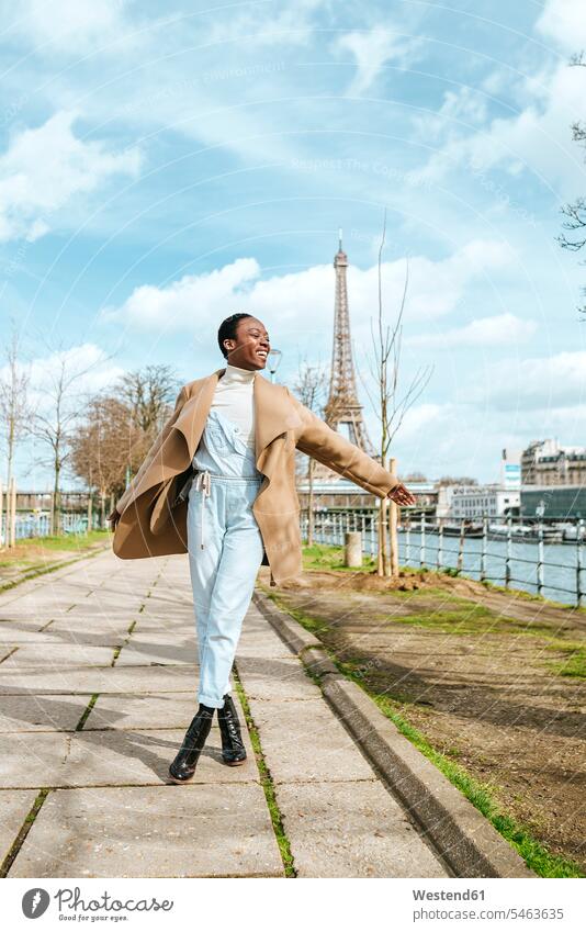Frankreich, Paris, Glückliche Frau zu Fuß am Flussufer mit dem Eiffelturm im Hintergrund glücklich glücklich sein glücklichsein weiblich Frauen Touristin gehen