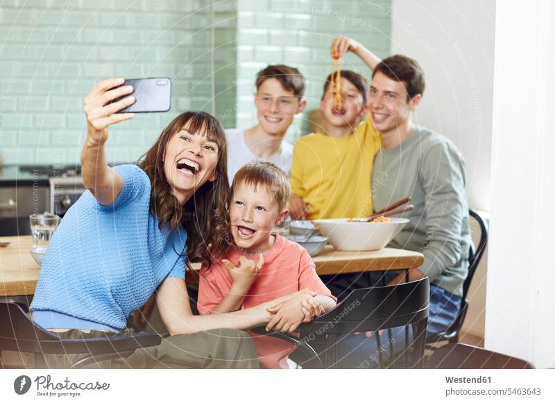Mutter und ihre vier Söhne machen Smartphone-Selfies beim Mittagessen daheim zu Hause drinnen Innenaufnahmen Leute Menschen People Person Personen Familien