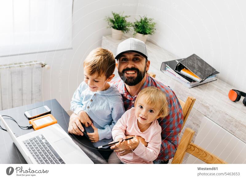 Vater, der zu Hause arbeitet, mit Laptop und seinen Kindern auf dem Schoß Tochter Töchter Papas Väter Vati Vatis Papis lachen arbeiten Arbeit Sohn Söhne