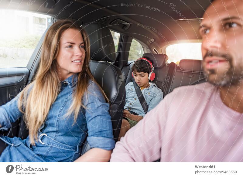 Familie unterwegs mit einem Jungen mit Kopfhörern Familien Auto Wagen PKWs Automobil Autos Kopfhoerer fahren fahrend fahrender fahrendes Mensch Menschen Leute