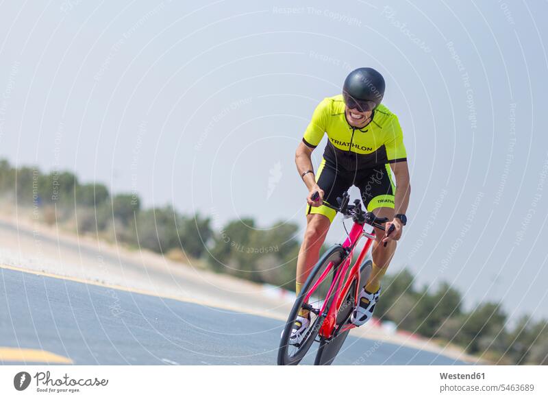 Entschlossener Radfahrer fährt Fahrrad auf der Strasse gegen den klaren Himmel, Dubai, Vereinigte Arabische Emirate Farbaufnahme Farbe Farbfoto Farbphoto