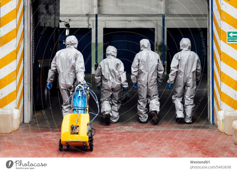 Rückansicht von Sanitärmitarbeitern, die ein Lager mit Dekontaminierungschemikalien betreten Farbaufnahme Farbe Farbfoto Farbphoto Coronavirus Covid-19 Virus