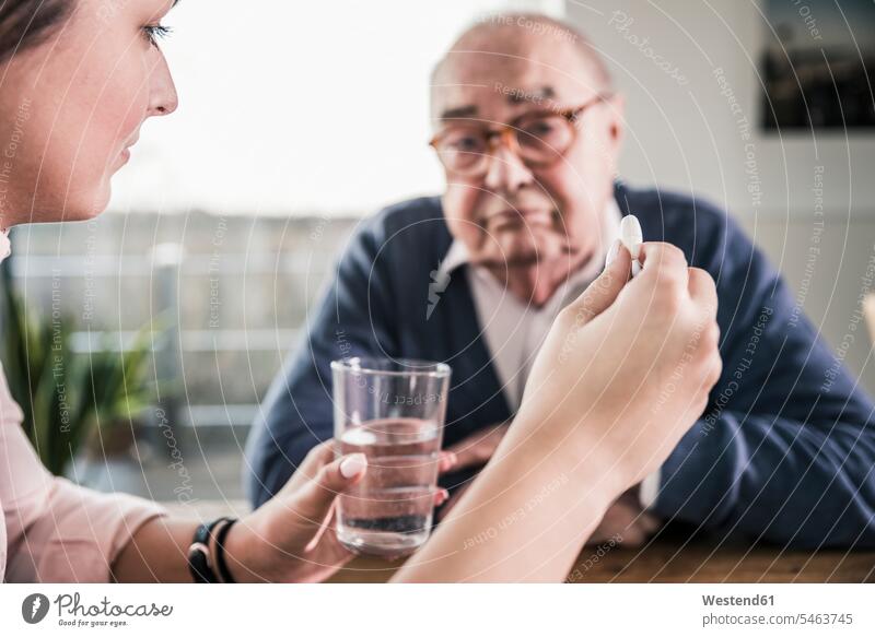 Frau hält Pille und Glas Wasser für älteren Mann Senior ältere Männer älterer Mann Senioren Tablette Pillen Tabletten weiblich Frauen Getränk Getraenk Getränke
