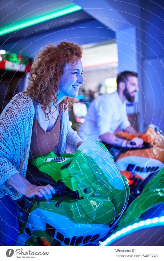Frau spielt und hat Spaß mit einem Fahrsimulator in einer Spielhalle Leute Menschen People Person Personen gelockt gelockte Haare gelocktes Haar lockig