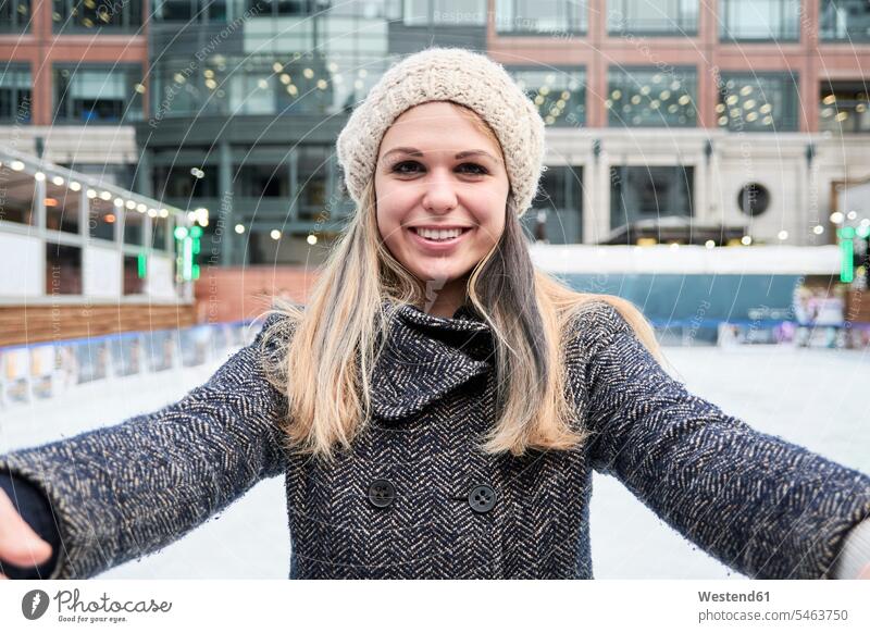 Blonde junge Frau schaut in die Kamera beim Skifahren auf einer Eisbahn tragen anhaben lachen weiblich Frauen Winter winterlich Winterzeit Spaß Spass Späße