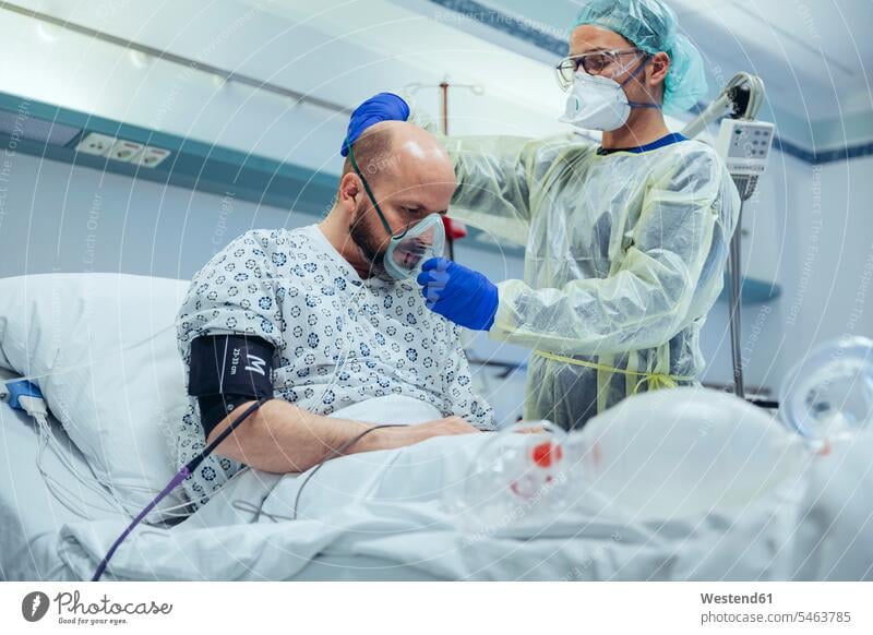 Arzt, der einen Patienten auf der Notfallstation eines Krankenhauses künstlich beatmet Leute Menschen People Person Personen Europäisch Kaukasier kaukasisch 2
