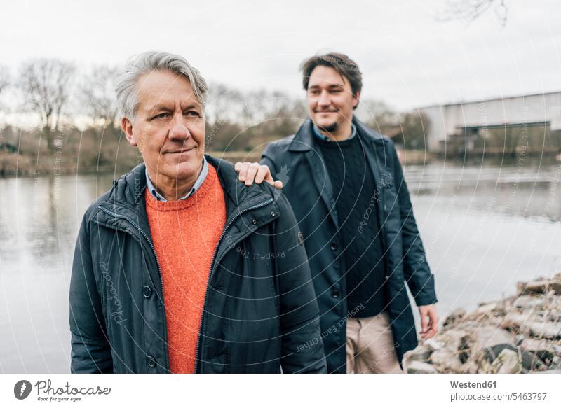 Zuversichtlicher älterer Mann und junger Mann stehen am Flussufer Selbstvertrauen selbstbewusst Vertrauen Männer männlich stehend steht Ufer Erwachsener