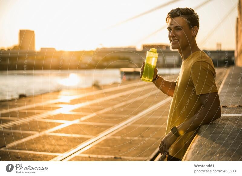 Mann mit Wasserflasche nach dem Training bei klarem Himmel Farbaufnahme Farbe Farbfoto Farbphoto Außenaufnahme außen draußen im Freien Sportkleidung