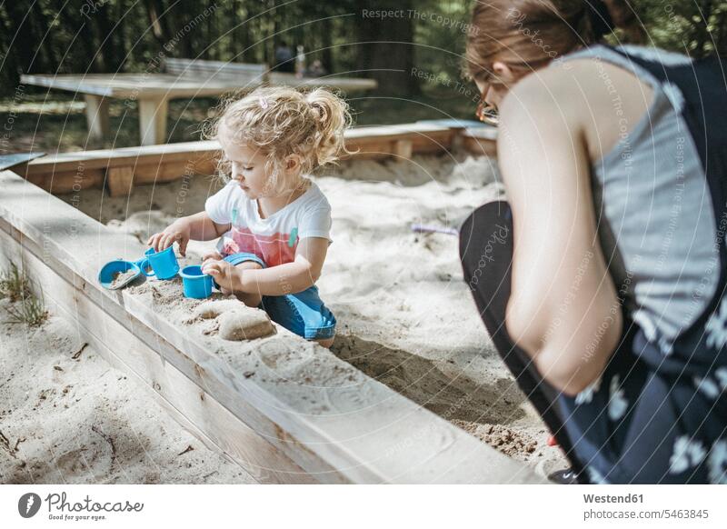 Mutter spielt mit kleiner Tochter im Sandkasten auf einem Spielplatz Sandkästen Sandkiste Sandkisten Spielplätze Spielfeld Spielplaetze Mami Mutti Mütter Mama