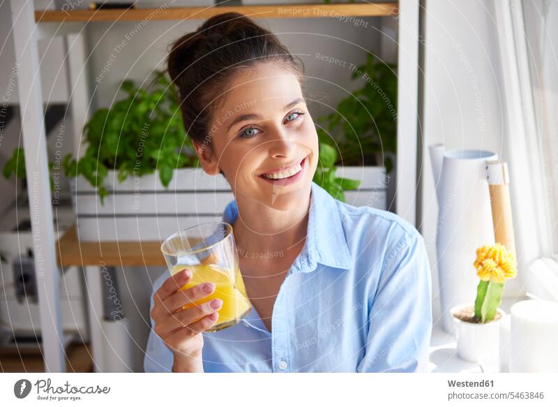 Junge Frau trinkt Orangensaft in ihrer Küche Glas Trinkgläser Gläser Trinkglas Portrait Porträts Portraits Blickkontakt Augenkontakt Frische frisch Brustbild
