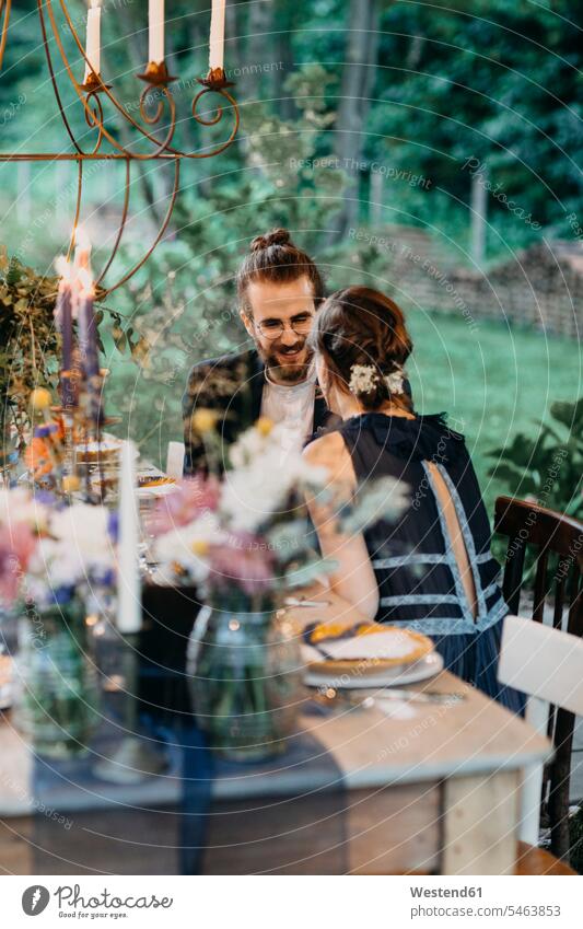 Glückliche Braut und Bräutigam sitzen an festlich gedeckten Tisch im Freien sitzend sitzt Bräute Tische glücklich glücklich sein glücklichsein Brautpaar
