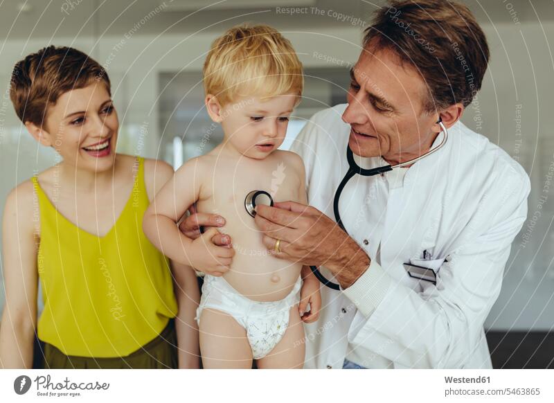 Kinderarzt untersucht Kleinkind mit Stethoskop, Mutter steht daneben Abhören abhorchen Auskultation abhoeren Junge männliche Babys männliches Baby