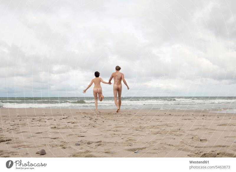 Ein nacktes Paar rennt zum Meer und hält sich an den Händen rennen gefühlvoll Emotionen Empfindung Empfindungen fühlen Gefühl Gefühle lieben Erwartung