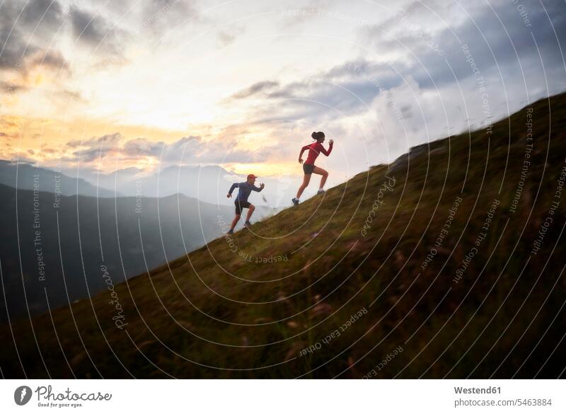 Mann und Frau laufen in den Bergen bergauf früh Frühe Morgen Leistungen frei Miteinander Zusammen Schnelligkeit Anreiz Ansporn Antrieb motivieren motiviert