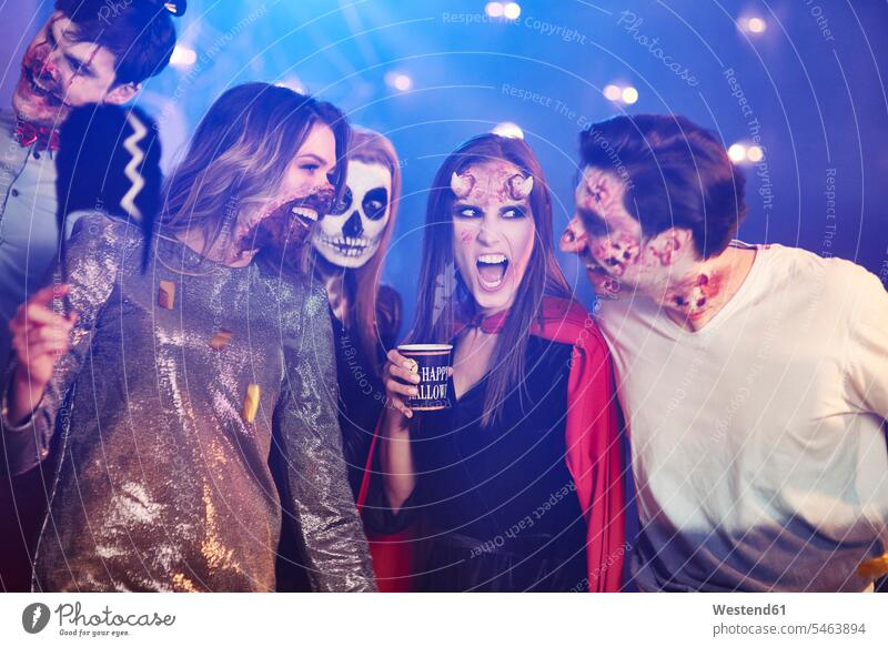 Freunde in Halloween-Kostümen tanzen zwischen Konfetti Party Parties Partys maskiert Abend vor Allerheiligen feiern lachen trinken Feier Fest Festlichkeit