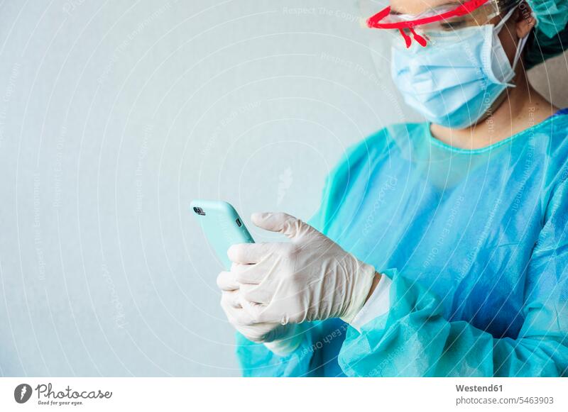 Reife Zahnärztin benutzt Mobiltelefon, während sie in der Klinik an einer weißen Wand steht Farbaufnahme Farbe Farbfoto Farbphoto Spanien Innenaufnahme