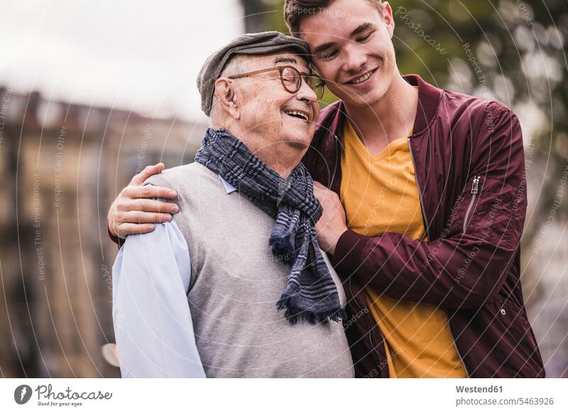 Glücklicher älterer Mann Kopf an Kopf mit seinem erwachsenen Enkel im Freien Leute Menschen People Person Personen Europäisch Kaukasier kaukasisch 2 2 Menschen