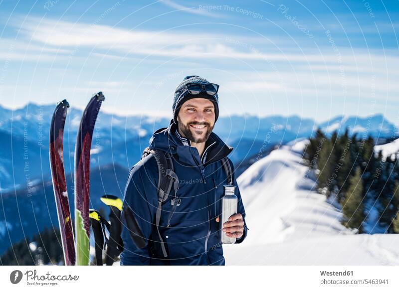 Deutschland, Bayern, Brauneck, Porträt eines lächelnden Mannes auf einer Skitour im Winter in den Bergen, der eine Pause macht Männer männlich Portrait Porträts