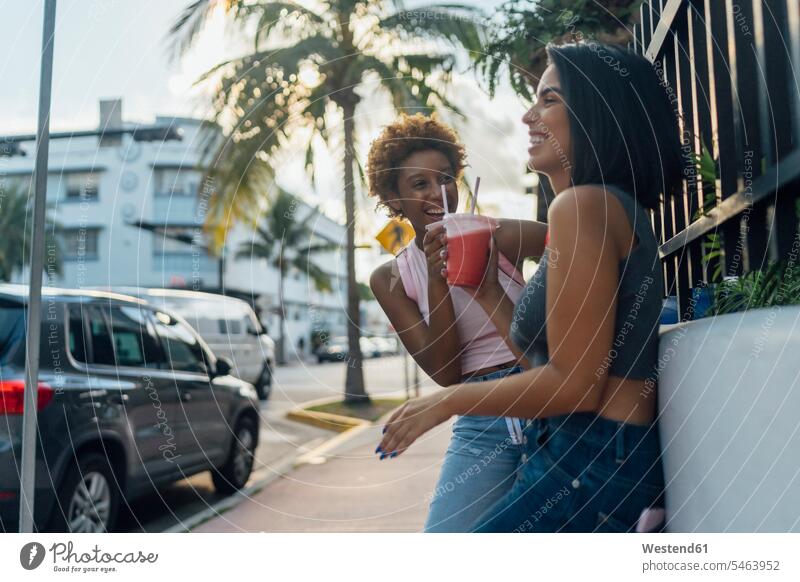 USA, Florida, Miami Beach, zwei glückliche Freundinnen bei einem Softdrink in der Stadt Erfrischungsgetränk Erfrischungsgetraenk staedtisch städtisch Glück