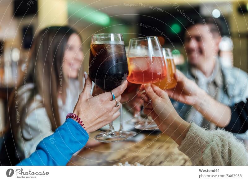 Freunde stoßen mit einem Getränk über dem Tisch in der Bar an Farbaufnahme Farbe Farbfoto Farbphoto Innenaufnahme Innenaufnahmen innen drinnen 16-17 Jahre