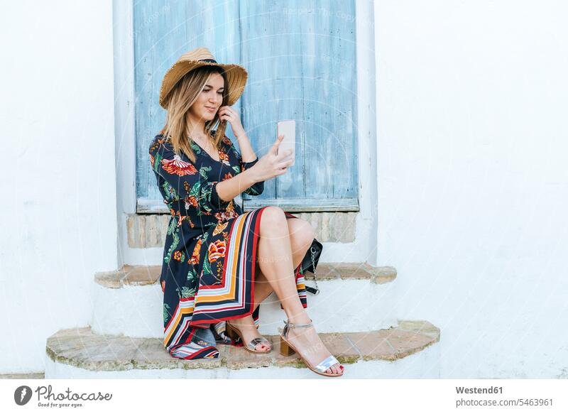 Spanien, Cadiz, Vejer de la Frontera, modische Frau macht Selfie mit Handy vor blauer Tür weiblich Frauen Selfies Smartphone iPhone Smartphones Türen blaues