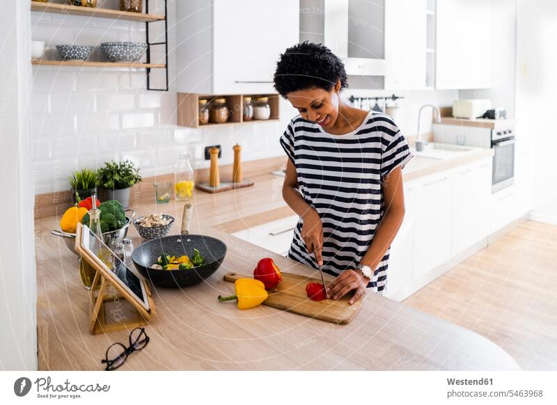 Junge Frau mit Tablette kocht zu Hause in der Küche und schneidet Gemüse Leute Menschen People Person Personen Alleinstehende Alleinstehender Singles