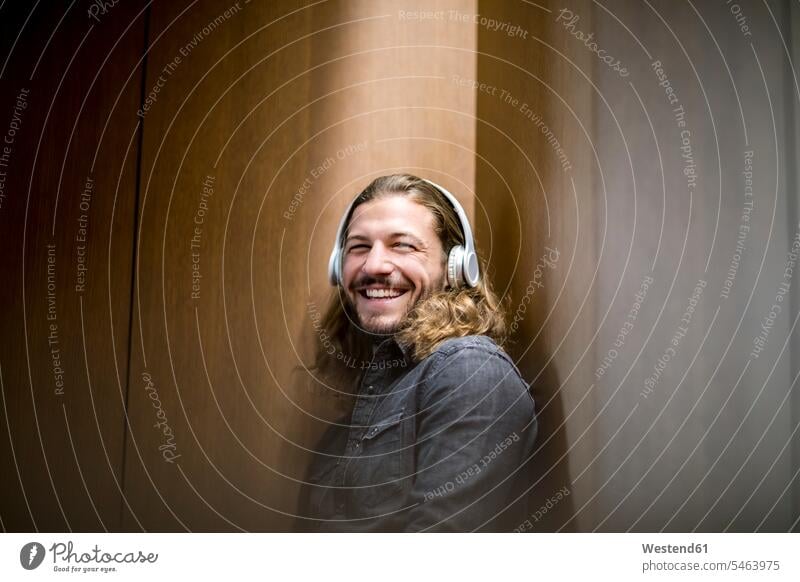 Porträt eines lachenden Mannes, der mit Kopfhörern Musik hört hören hoeren Kopfhoerer Portrait Porträts Portraits positiv Emotion Gefühl Empfindung Emotionen