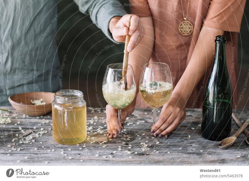 Mittelteil eines Mannes, der Wein im Glas rührt, während er mit seiner Freundin einen Cocktail zubereitet Farbaufnahme Farbe Farbfoto Farbphoto Innenaufnahme