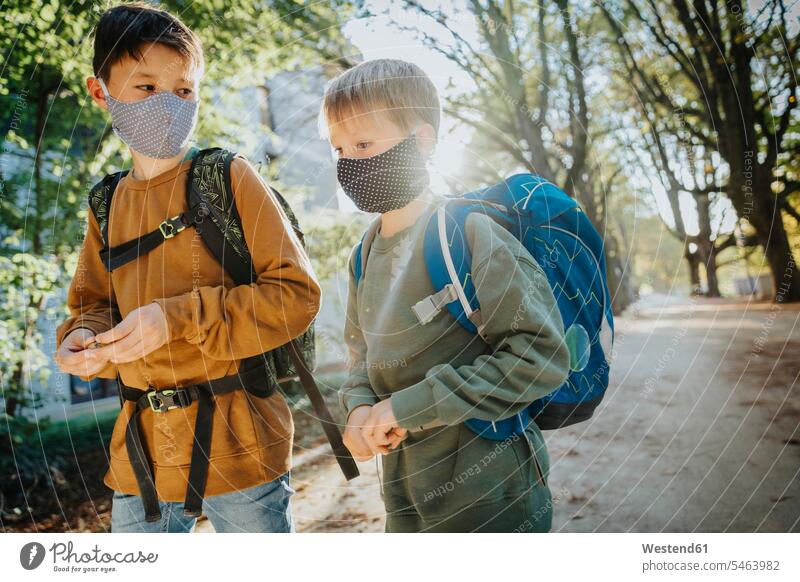 Brüder tragen eine schützende Gesichtsmaske, wenn sie an einem sonnigen Tag im öffentlichen Park spazieren gehen Farbaufnahme Farbe Farbfoto Farbphoto