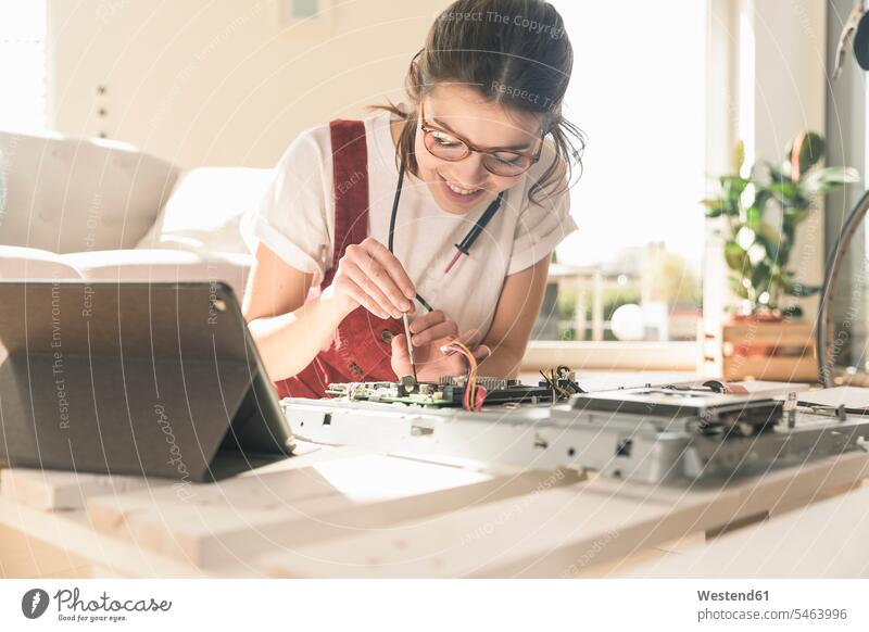 Junge Frau arbeitet an Computerausrüstung zu Hause neben Tablet Deutschland Kompetenz Fähigkeit Können Wohnen Aufmerksamkeit aufmerksam Zuwendung wachsam