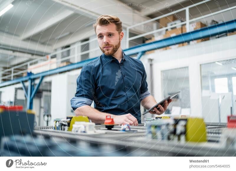 Junger Mann benutzt eine Tablette in einer Fabrik Job Berufe Berufstätigkeit Beschäftigung Jobs geschäftlich Geschäftsleben Geschäftswelt Geschäftsperson
