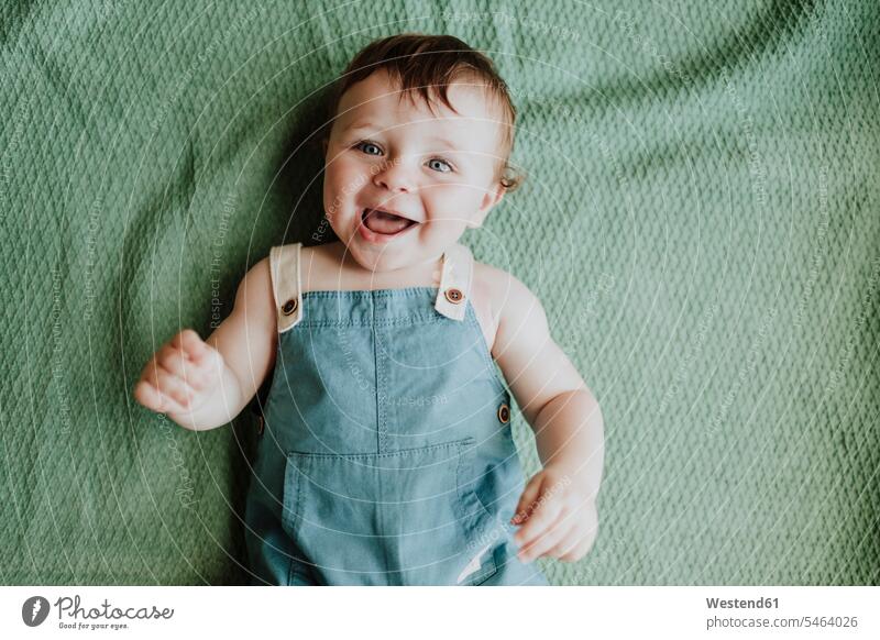 Nahaufnahme eines süßen Mädchens, das lacht, während es zu Hause auf einer Decke liegt Farbaufnahme Farbe Farbfoto Farbphoto Spanien Freizeitbeschäftigung Muße