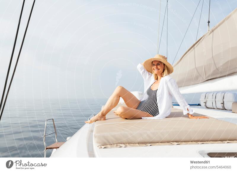 Reife Frau entspannt sich auf einem Katamaran und nimmt ein Sonnenbad Entspannung Entspannen relaxen entspannen reife Frau reife Frauen Schiffsdeck Decks