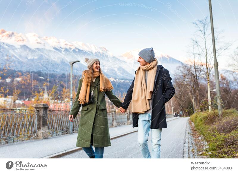 Österreich, Innsbruck, glückliches junges Paar beim gemeinsamen Spaziergang Hand in Hand zur Winterzeit Winter Zeit Pärchen Paare Partnerschaft spazierengehen