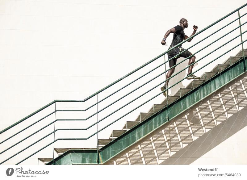 Mann in schwarzer Sportkleidung läuft Treppe hoch aufwärts nach oben hinauf Männer männlich Treppenaufgang Sportbekleidung Sportdress Kleidung schwarzen
