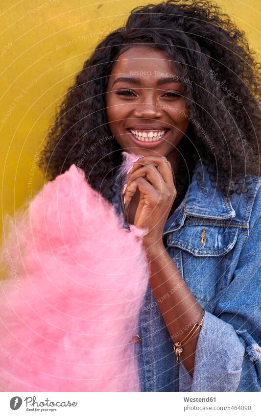 Porträt einer glücklichen jungen Frau mit rosa Zuckerwatte Leute Menschen People Person Personen Afrikanisch Afrikanische Abstammung dunkelhäutig Farbige